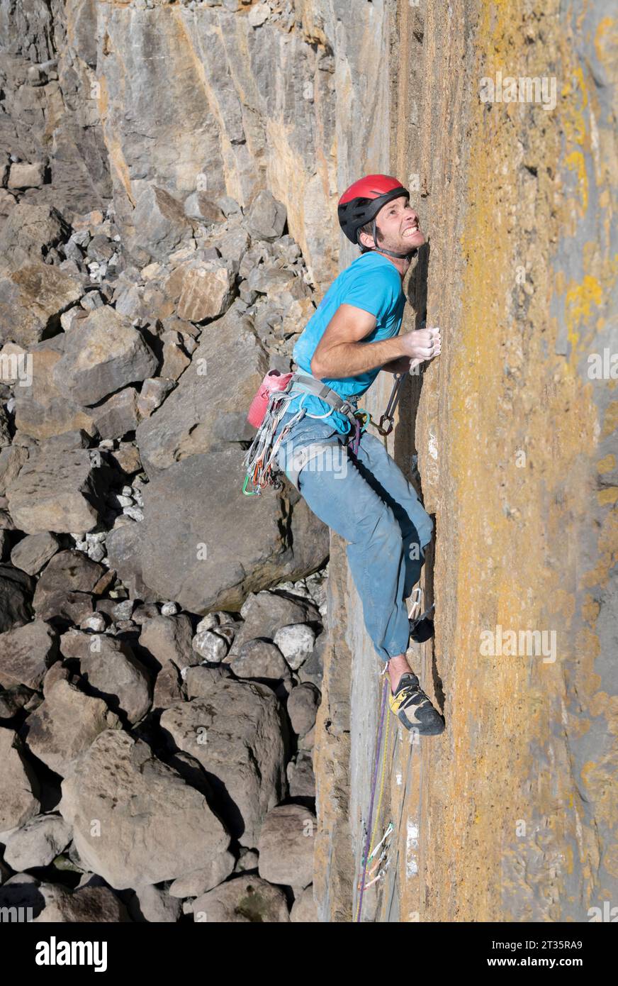 Determined man climbing rocky mountain at sunny day Stock Photo