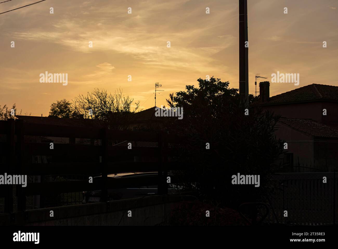 Golden hues of sunset filter through the silhouette of urban houses, casting a serene ambiance. Sunset Amidst City Homes Copyright: xfilippoxcarlotx 1373 Credit: Imago/Alamy Live News Stock Photo