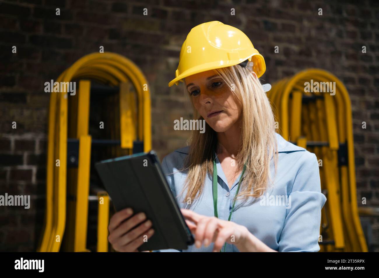 Blond engineer using tablet PC at factory Stock Photo