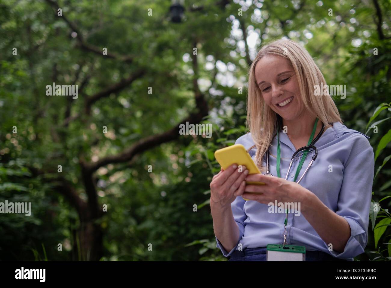 Smiling female doctor using smart phone Stock Photo