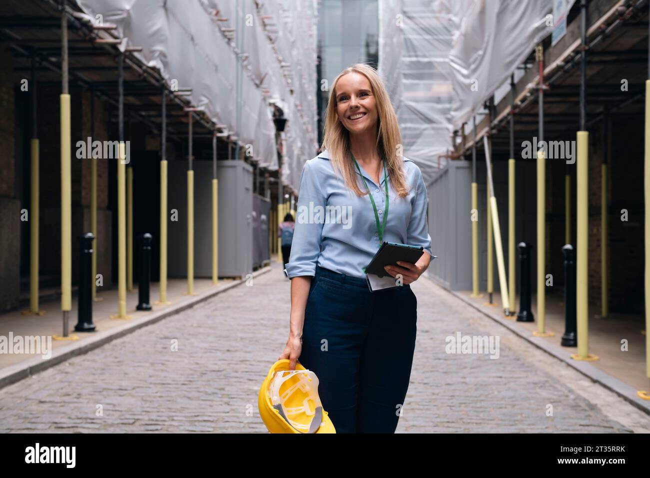 Happy blond engineer standing at construction site Stock Photo