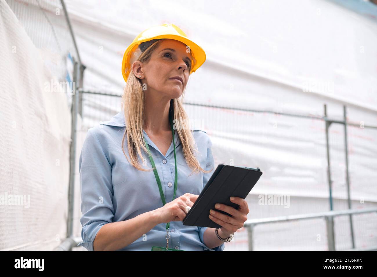 Contemplative engineer looking up holding tablet PC Stock Photo