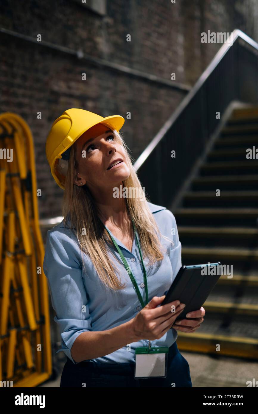 Contemplative engineer looking up standing in factory Stock Photo