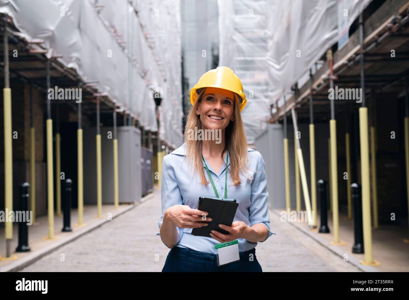 Thoughtful engineer holding tablet PC day dreaming at construction site Stock Photo