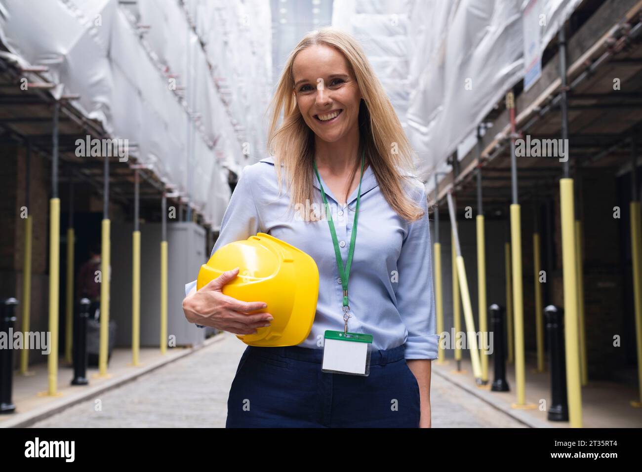 Smiling engineer holding hardhat standing at construction site Stock Photo