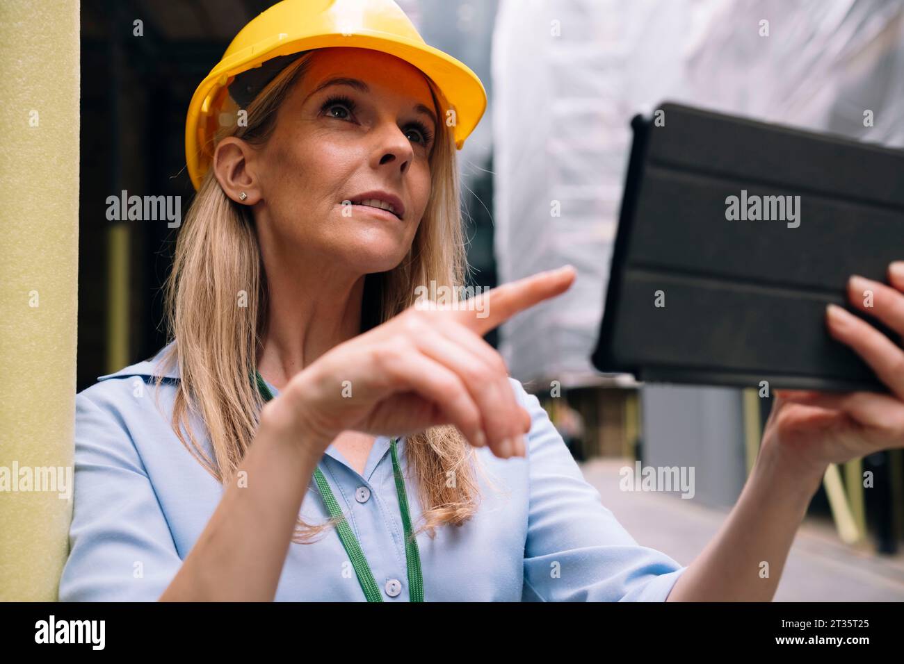 Engineer pointing at tablet PC leaning on pole Stock Photo
