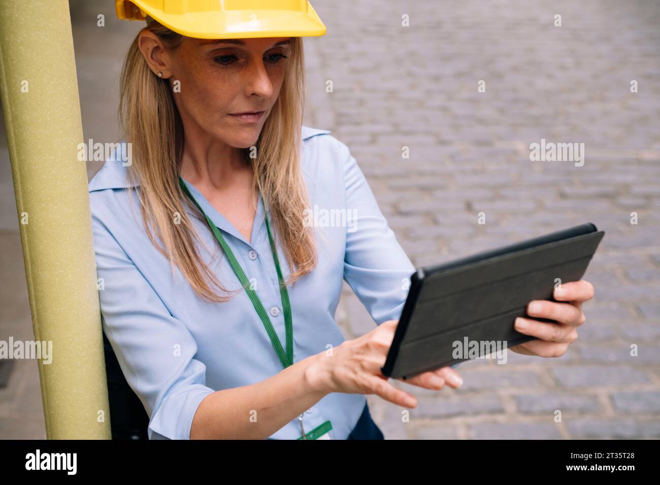Focused engineer using tablet PC leaning on pole Stock Photo