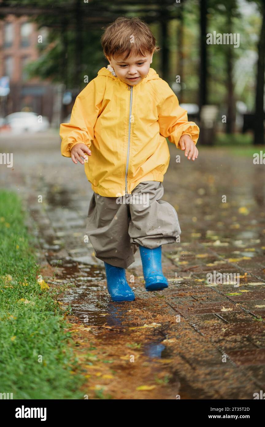 Boy in yellow raincoat playing in park Stock Photo Alamy