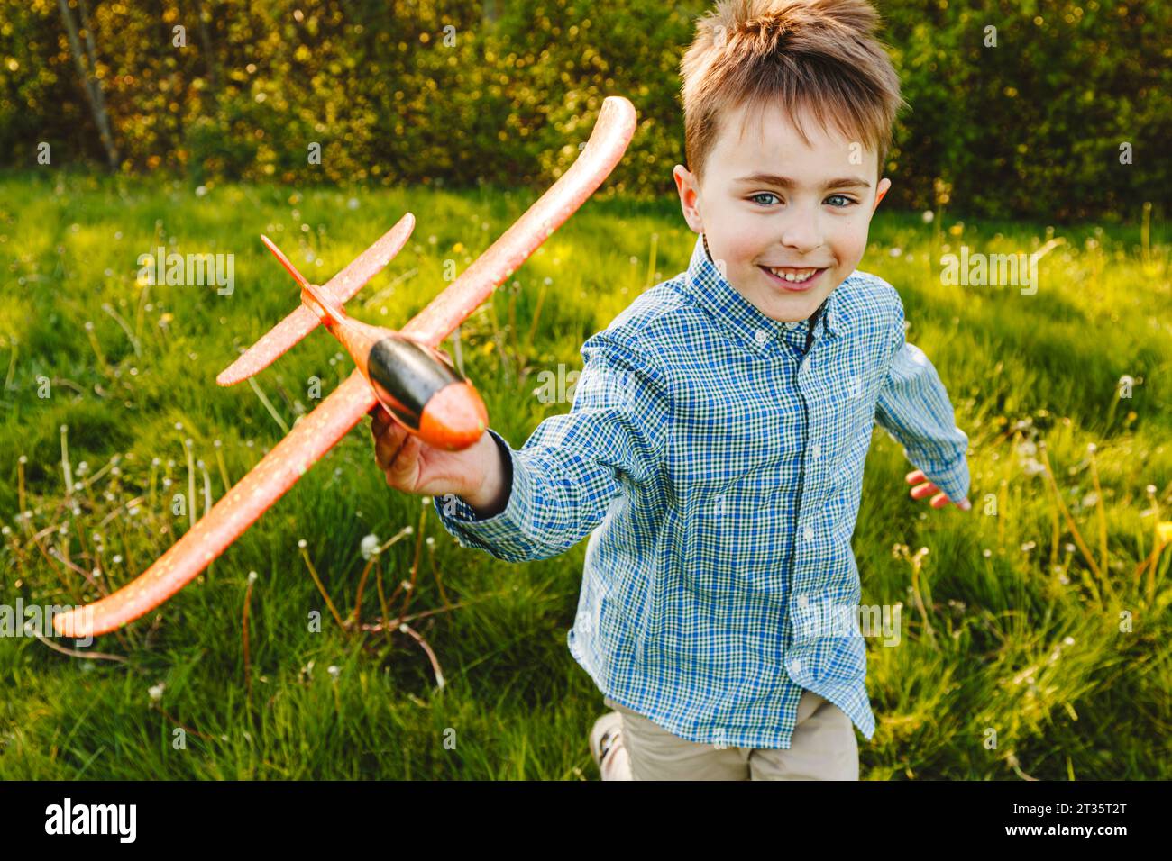 Smiling boy playing with toy airplane in garden Stock Photo - Alamy