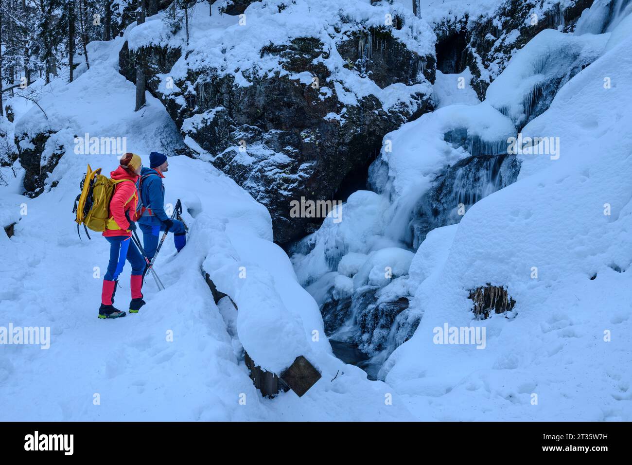 Couple in ski-wear hiking on snowcapped mountain Stock Photo