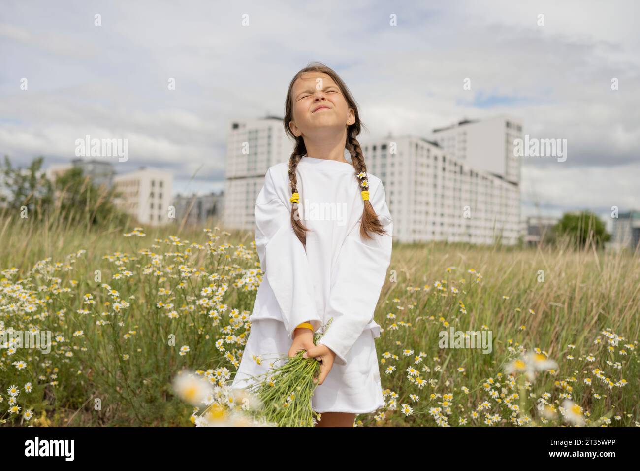 Girl with eyes closed holding bunch of daisy flowers in field Stock ...