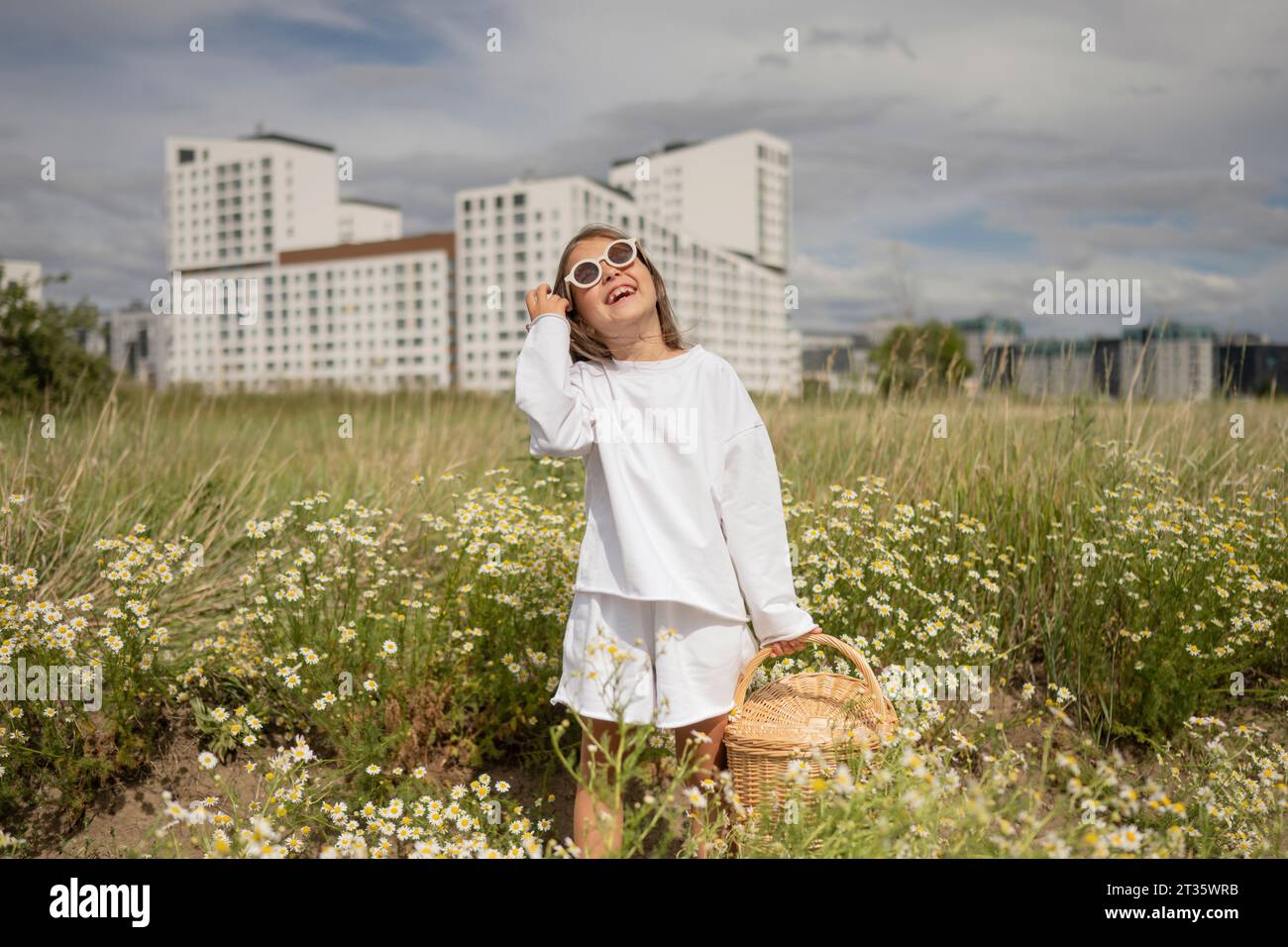 Smiling girl wearing sunglasses holding wicker basket in meadow Stock Photo