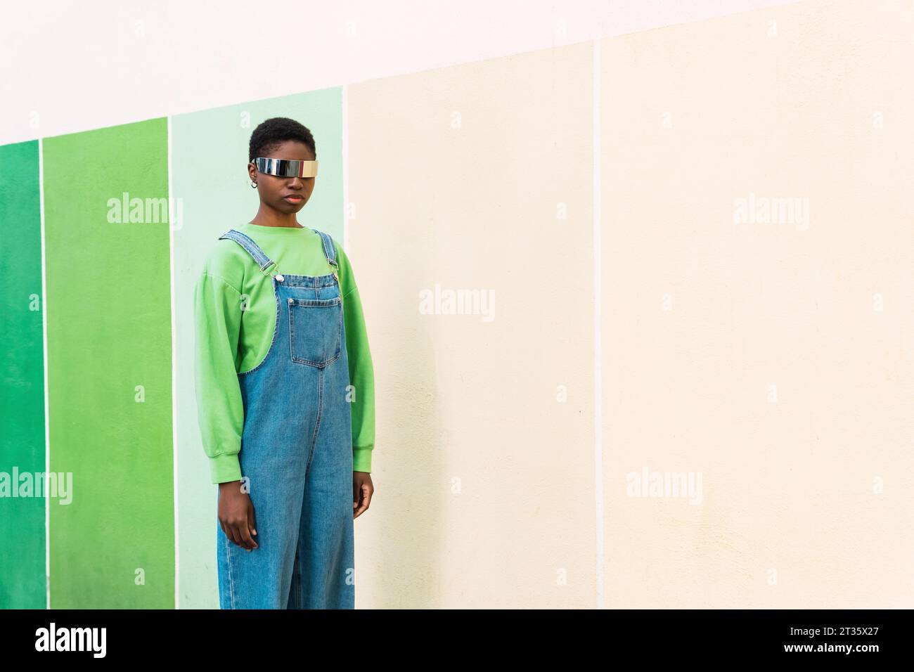 Young woman wearing smart glasses standing in front of multi colored wall Stock Photo