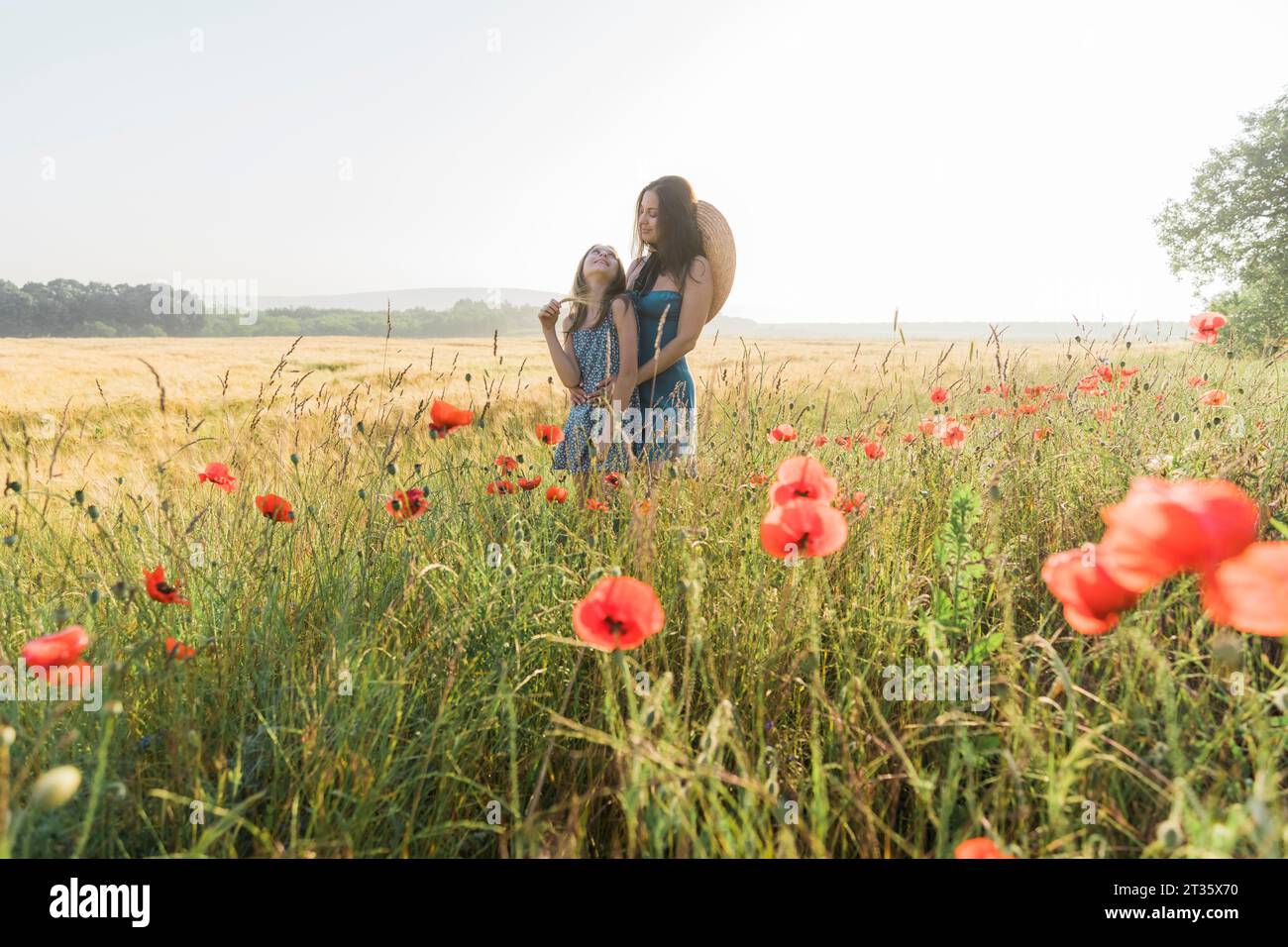 Mother and daughter spending leisure time in poppy field Stock Photo