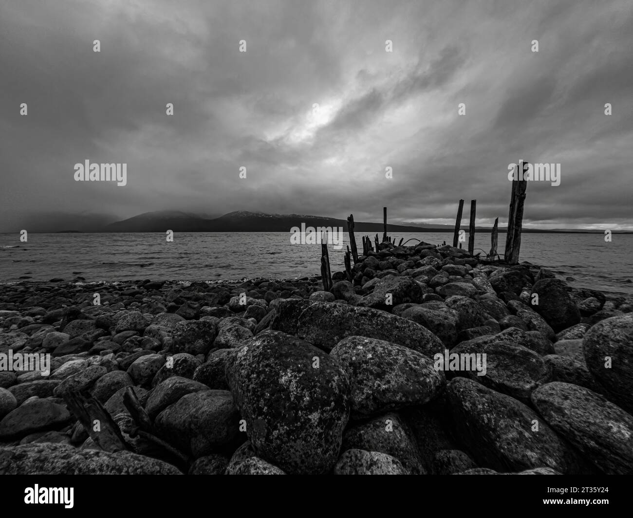 Rock pier on the lake shore with an incredible view of the mountains Stock Photo
