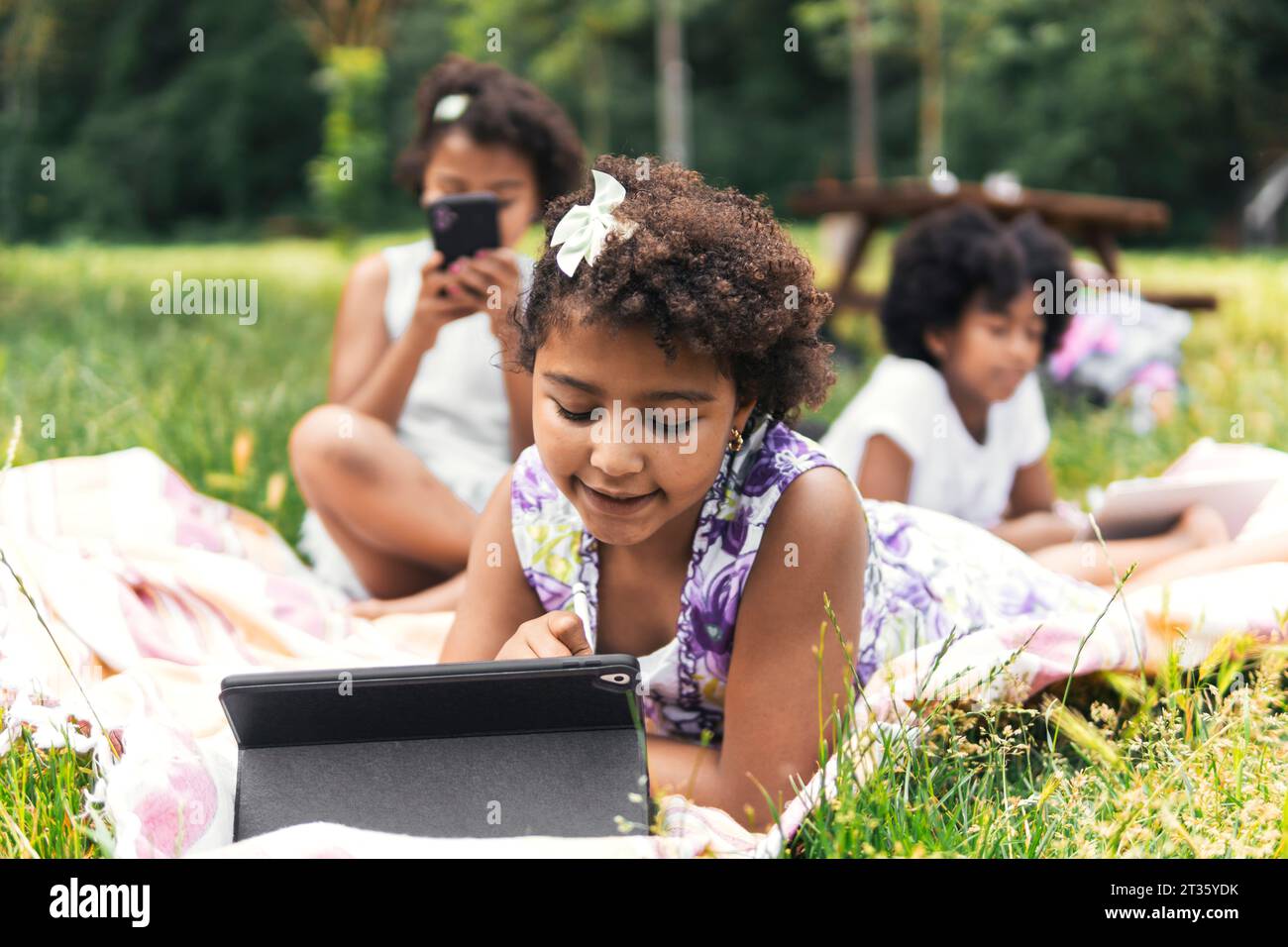Sisters spending leisure time with wireless technology in garden Stock Photo