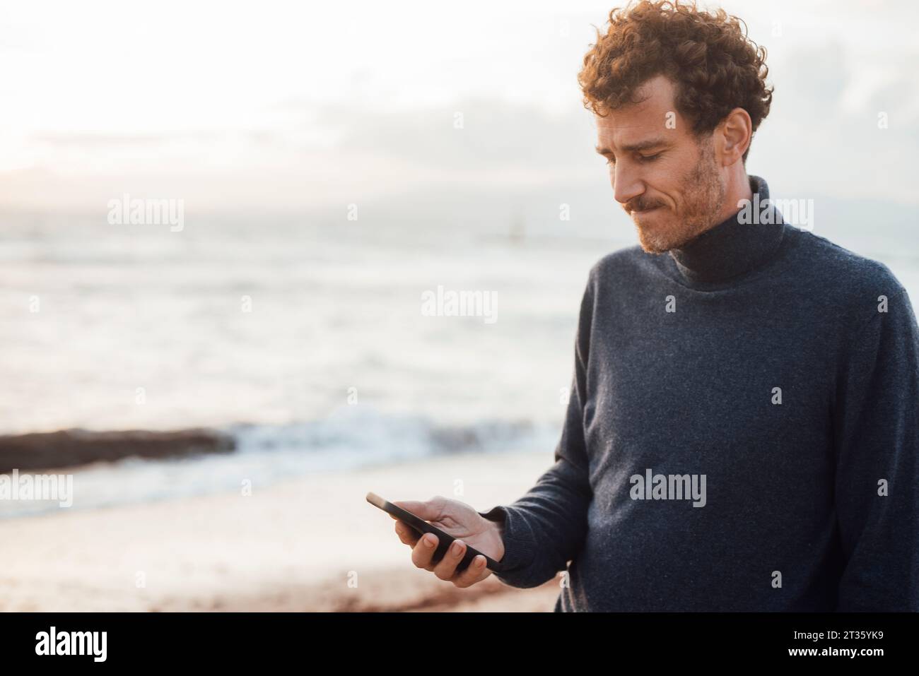 Man using smart phone at beach Stock Photo