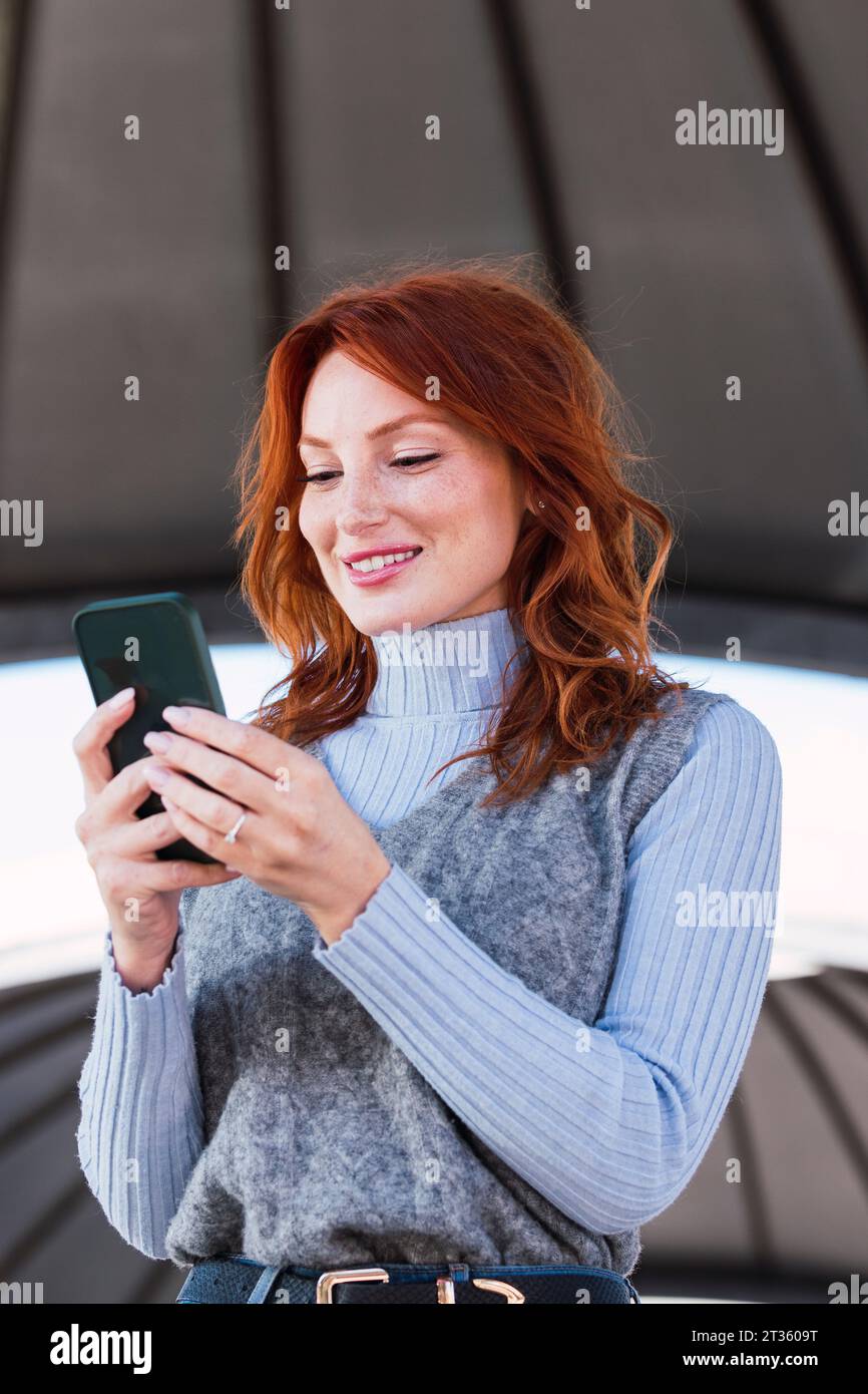 Happy redhead woman using mobile phone Stock Photo