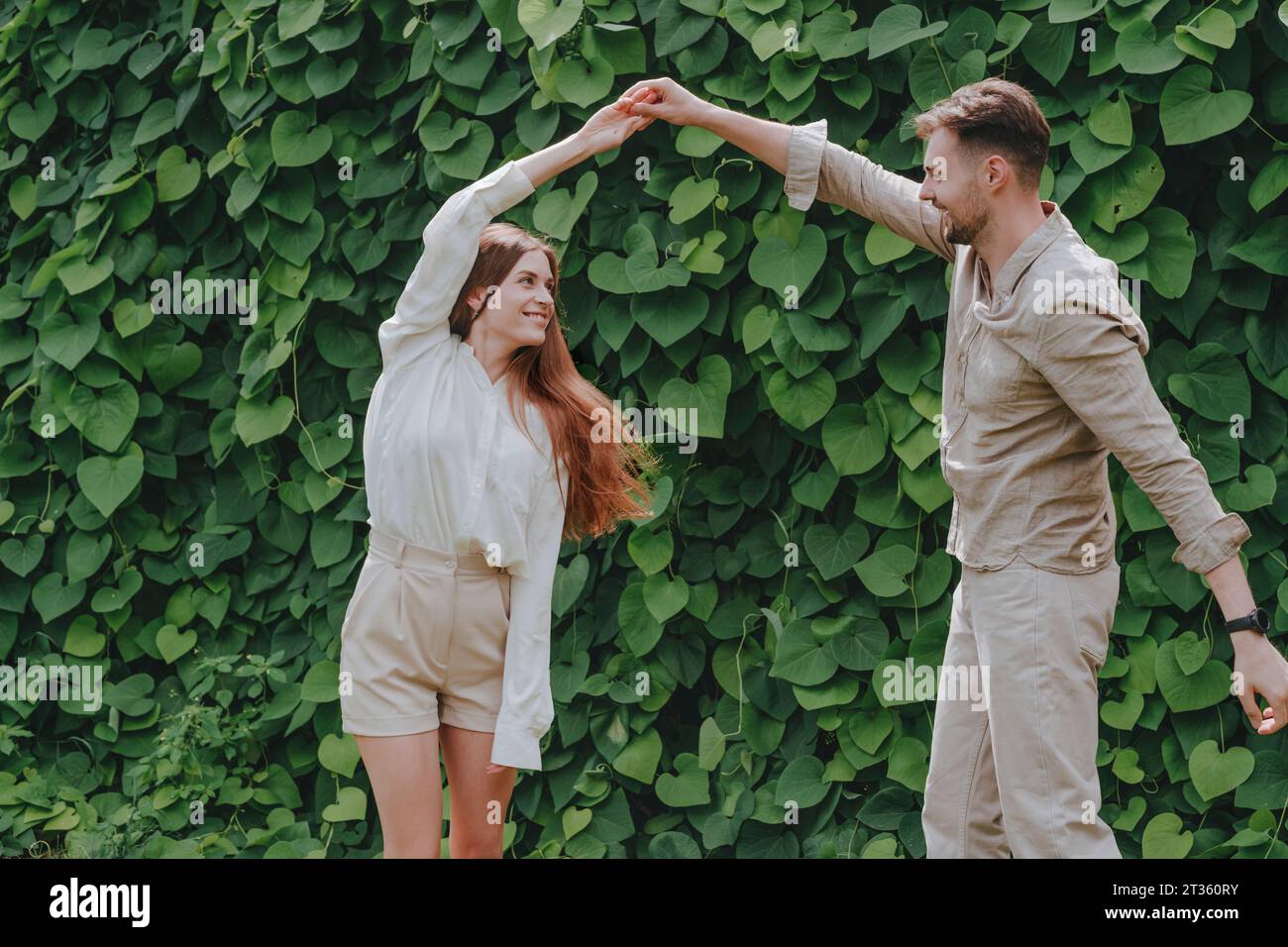 Happy couples dancing in front of plants in garden Stock Photo