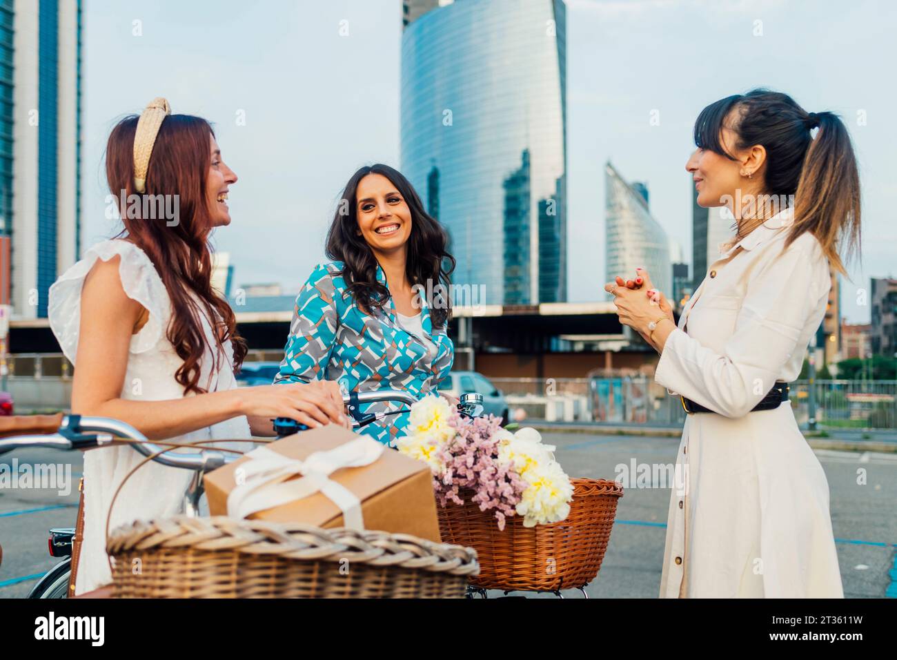 Happy woman with friends and bicycles in front of buildings Stock Photo