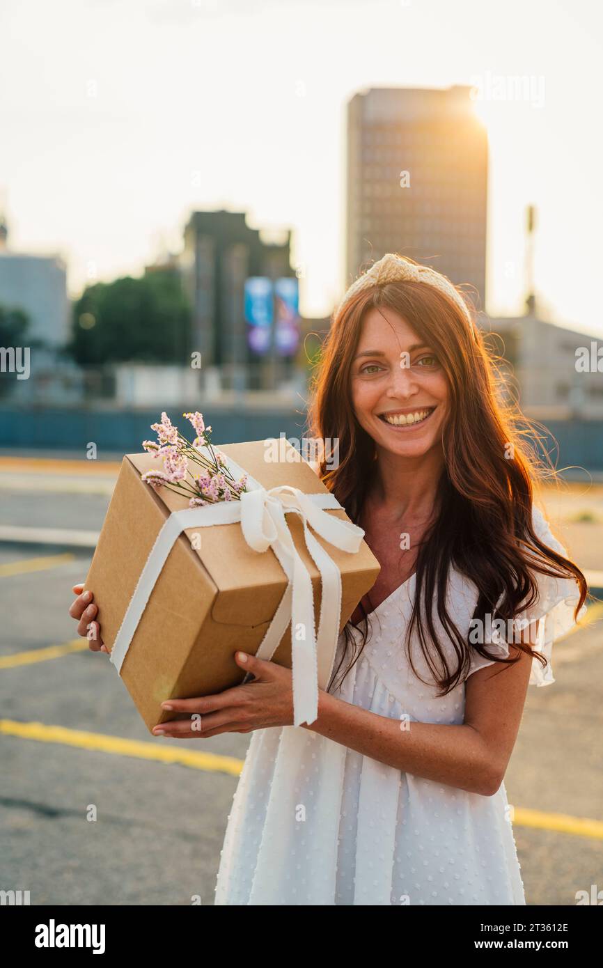 Happy woman holding gift box at sunset Stock Photo
