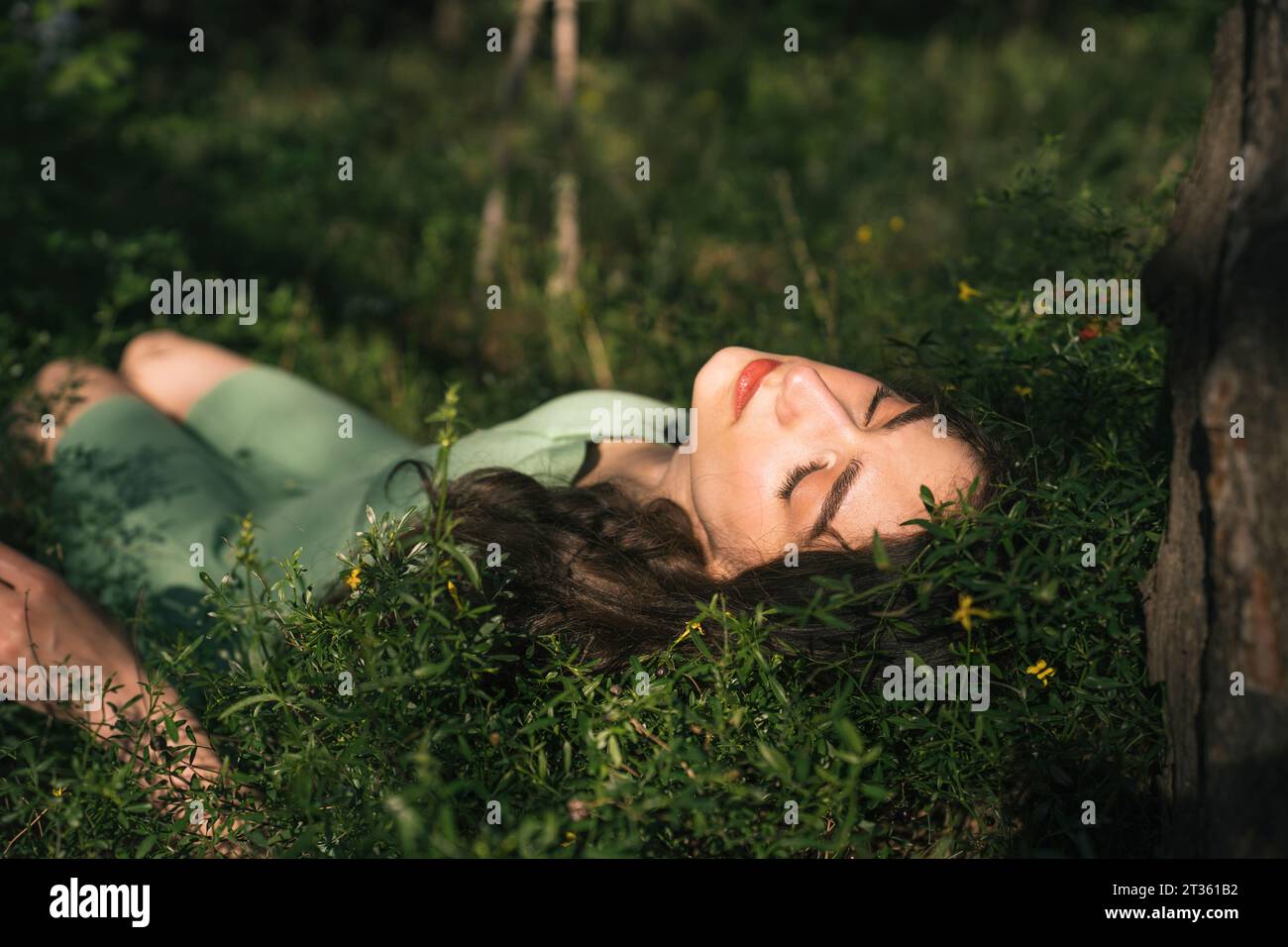 Woman with eyes closed lying on grass in forest Stock Photo - Alamy