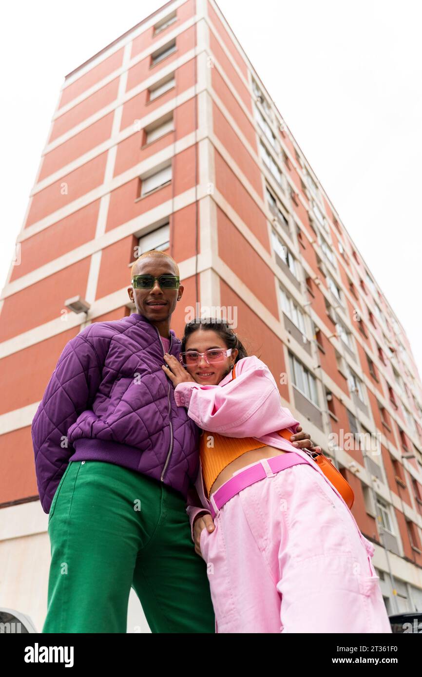 Smiling woman standing with non-binary person in front of building Stock Photo