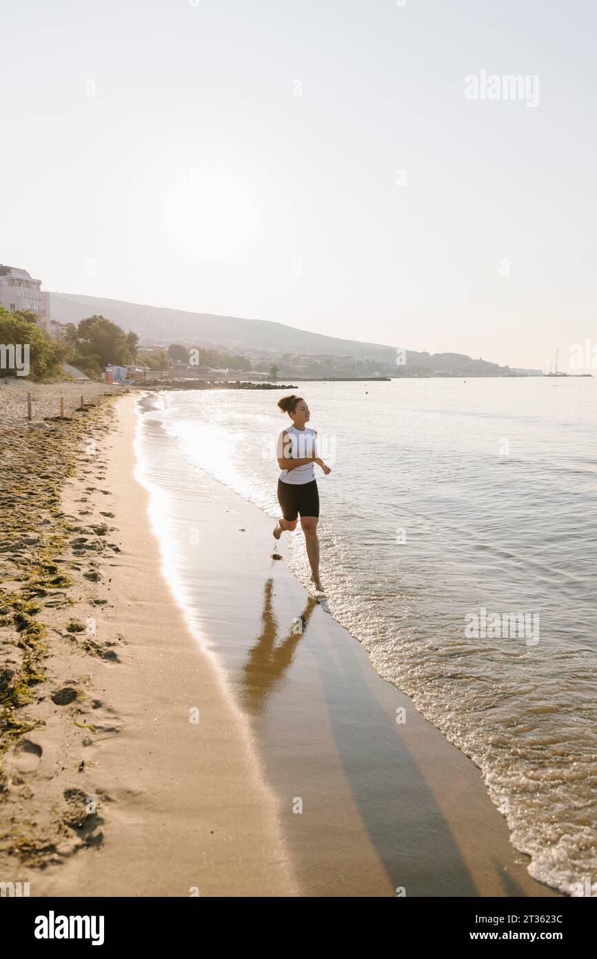 Woman running on coastline at beach Stock Photo