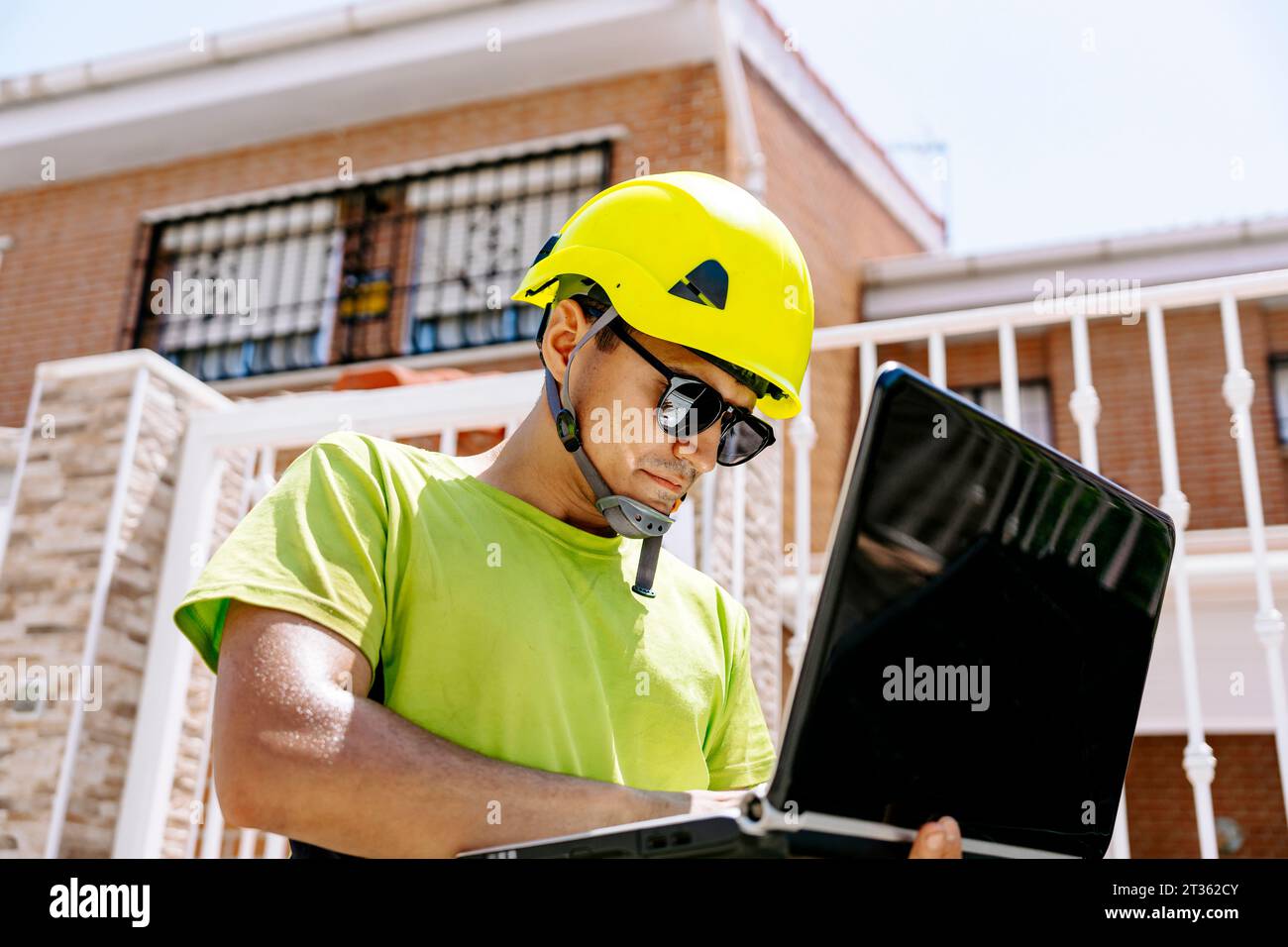 Engineer wearing hardhat working on laptop Stock Photo