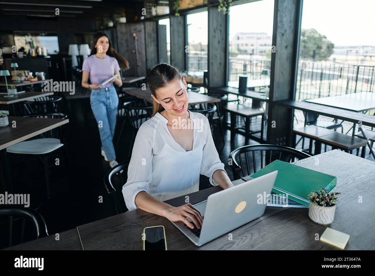 Two young women working together on sustainable resources project at coworking space Stock Photo