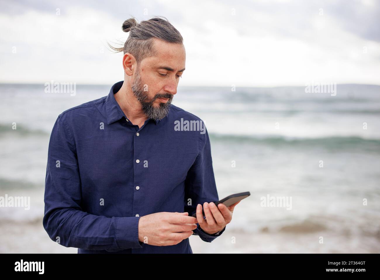 Mature man using smart phone at beach Stock Photo