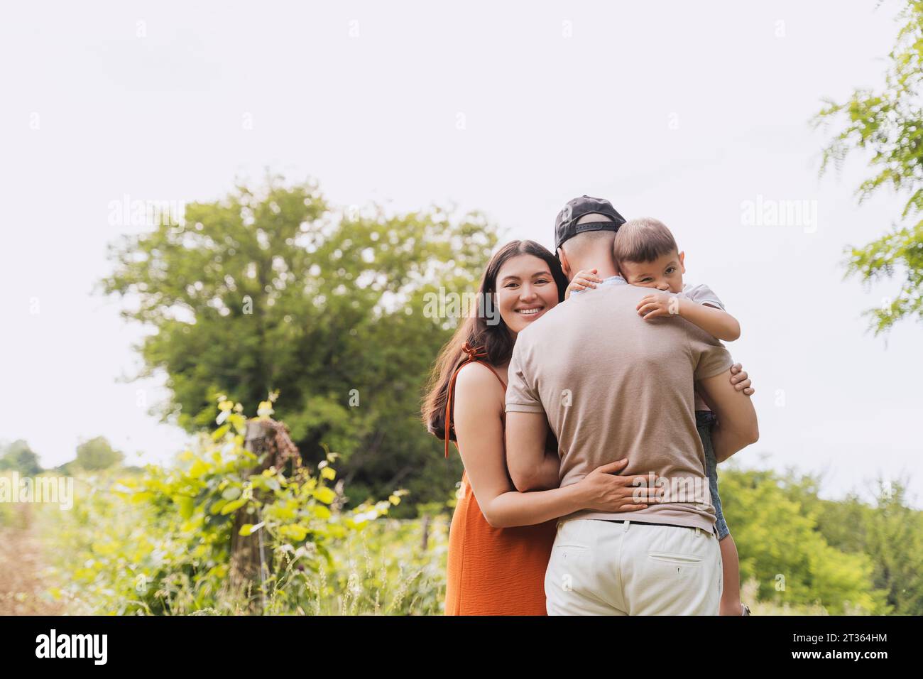 Smiling woman hugging family near plants Stock Photo