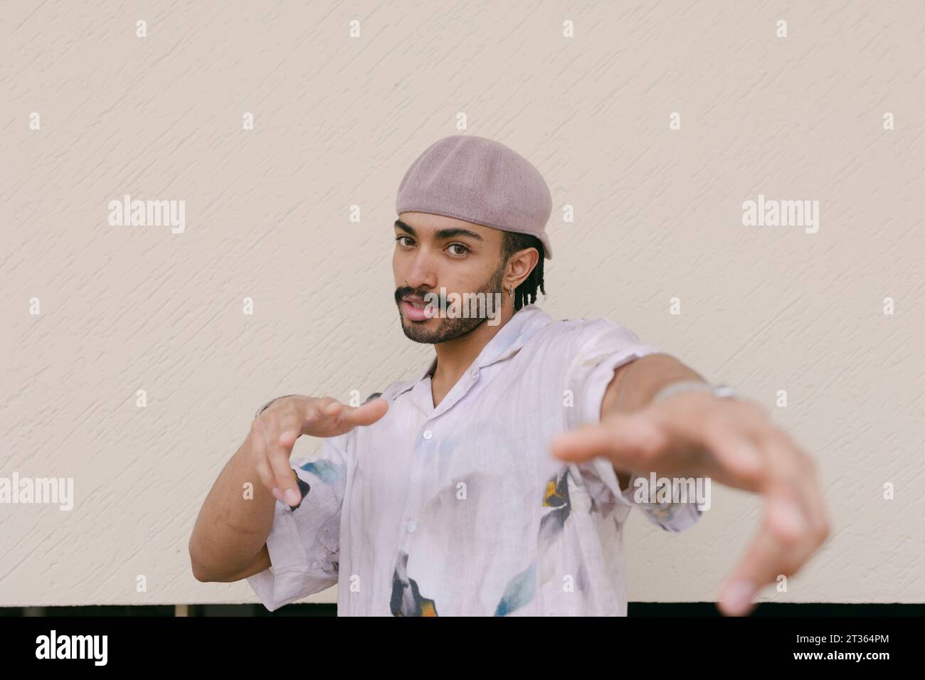 Young man gesturing in front of wall Stock Photo