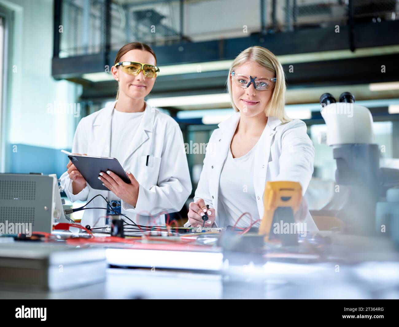 Smiling young scientists working in electronics laboratory Stock Photo