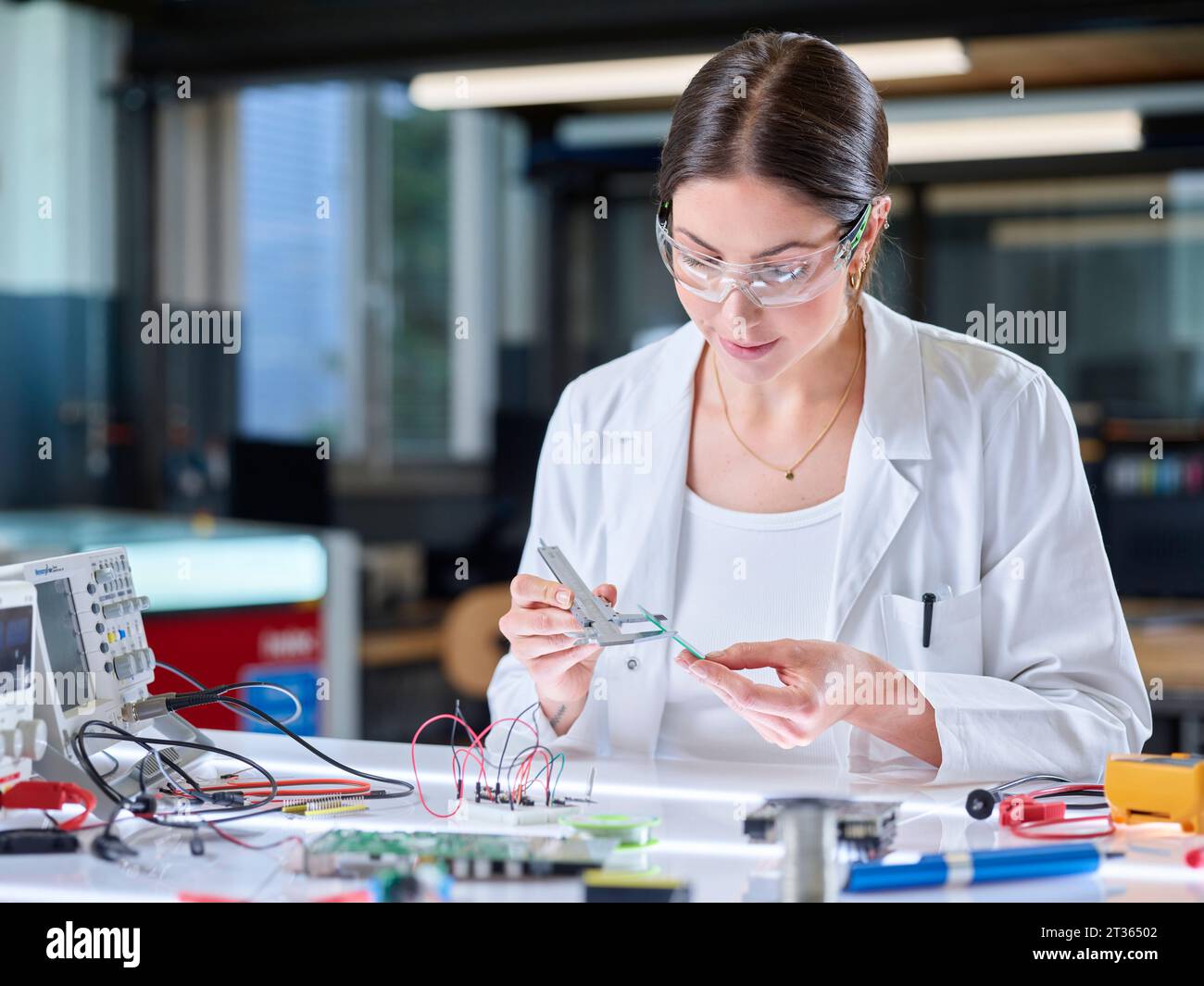Trainee measuring circuit board with caliper in laboratory Stock Photo