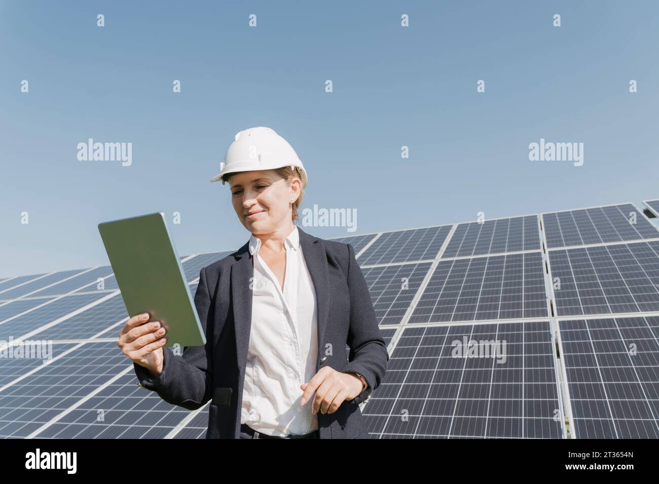 Smiling engineer using tablet PC in front of solar panels Stock Photo