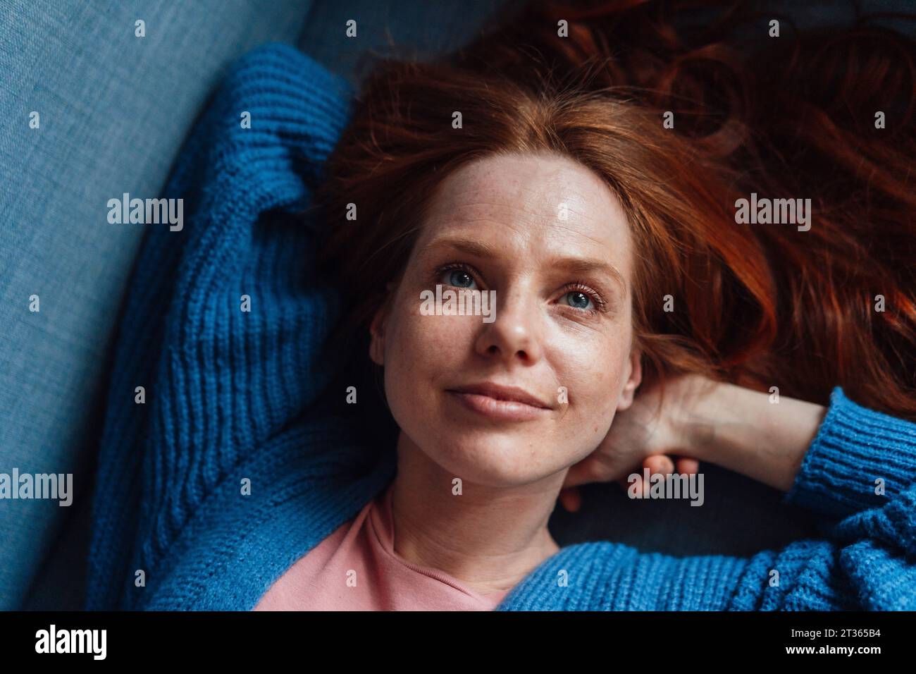 Smiling redhead woman relaxing on sofa Stock Photo