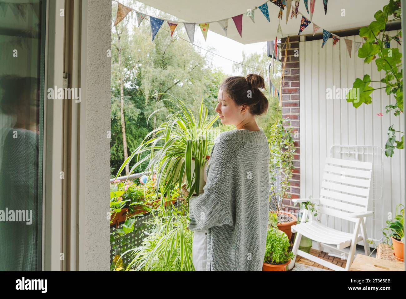 Teenage girl holding potted plant standing on balcony at home Stock ...