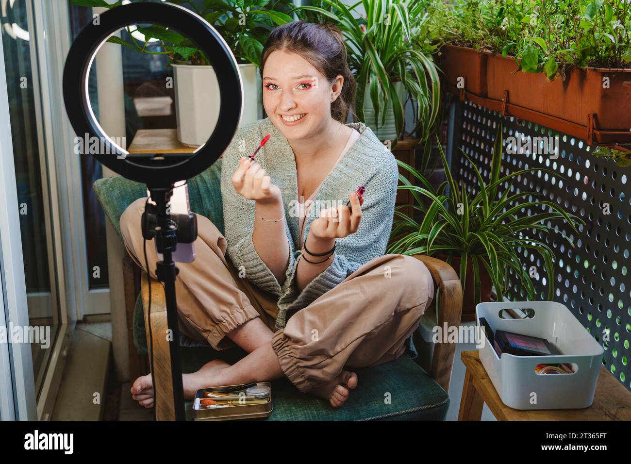 Vlogger with lipstick recording video on smart phone using ring light Stock Photo