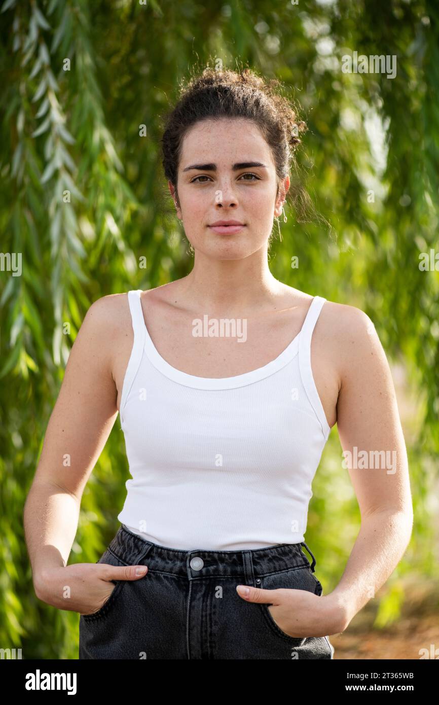 Young woman standing with hands in pockets Stock Photo