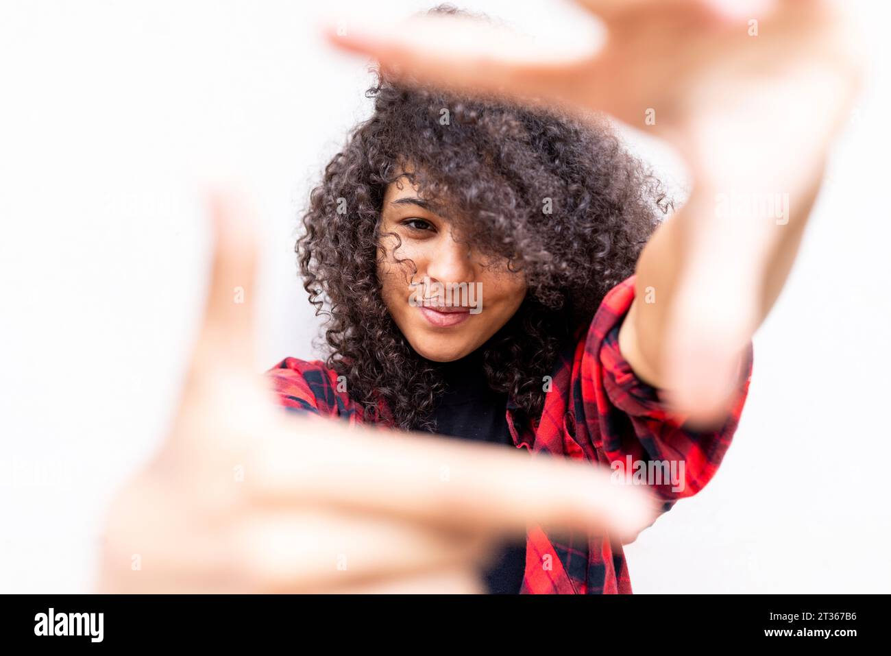 Smiling woman gesturing finger frame in front of wall Stock Photo - Alamy