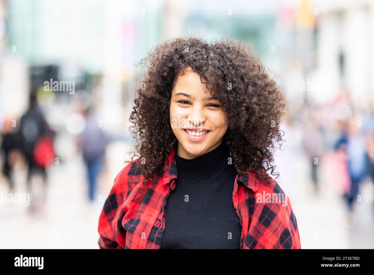 Smiling young woman with curly hair Stock Photo