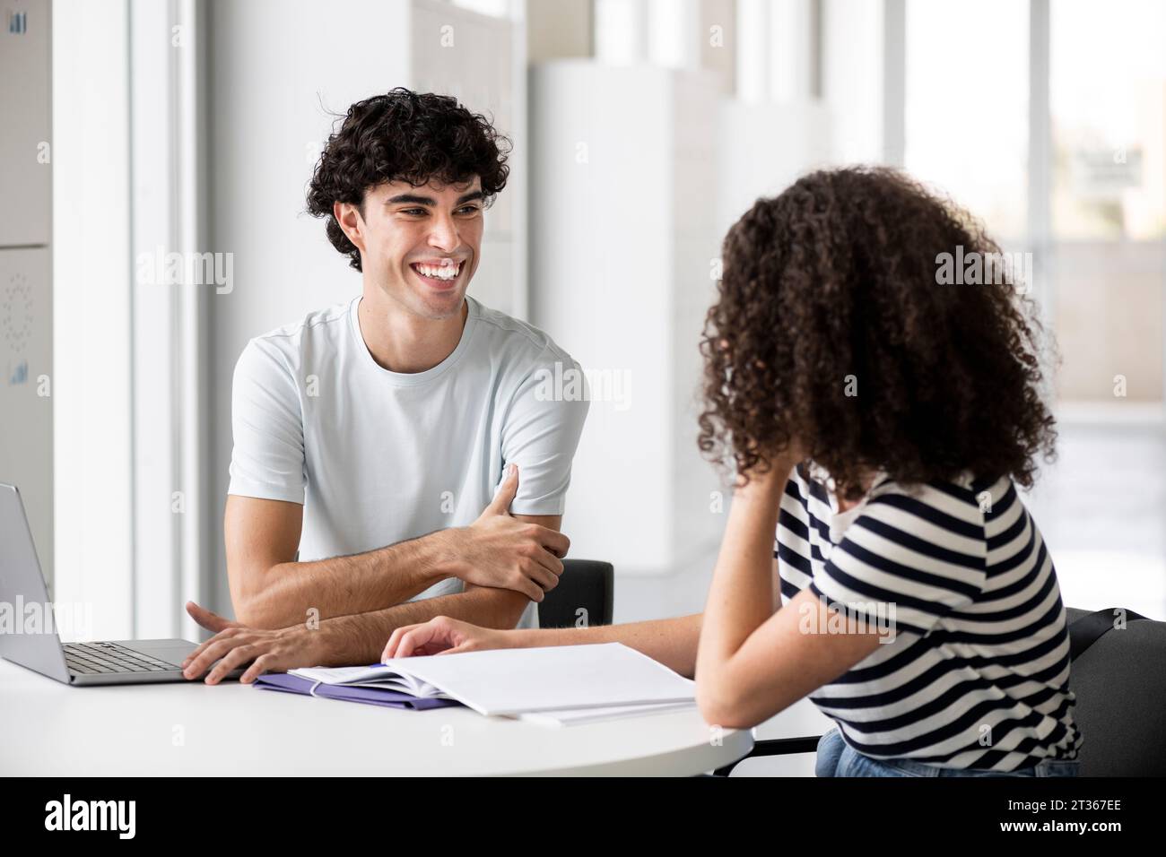Smiling students communicating at table in university Stock Photo