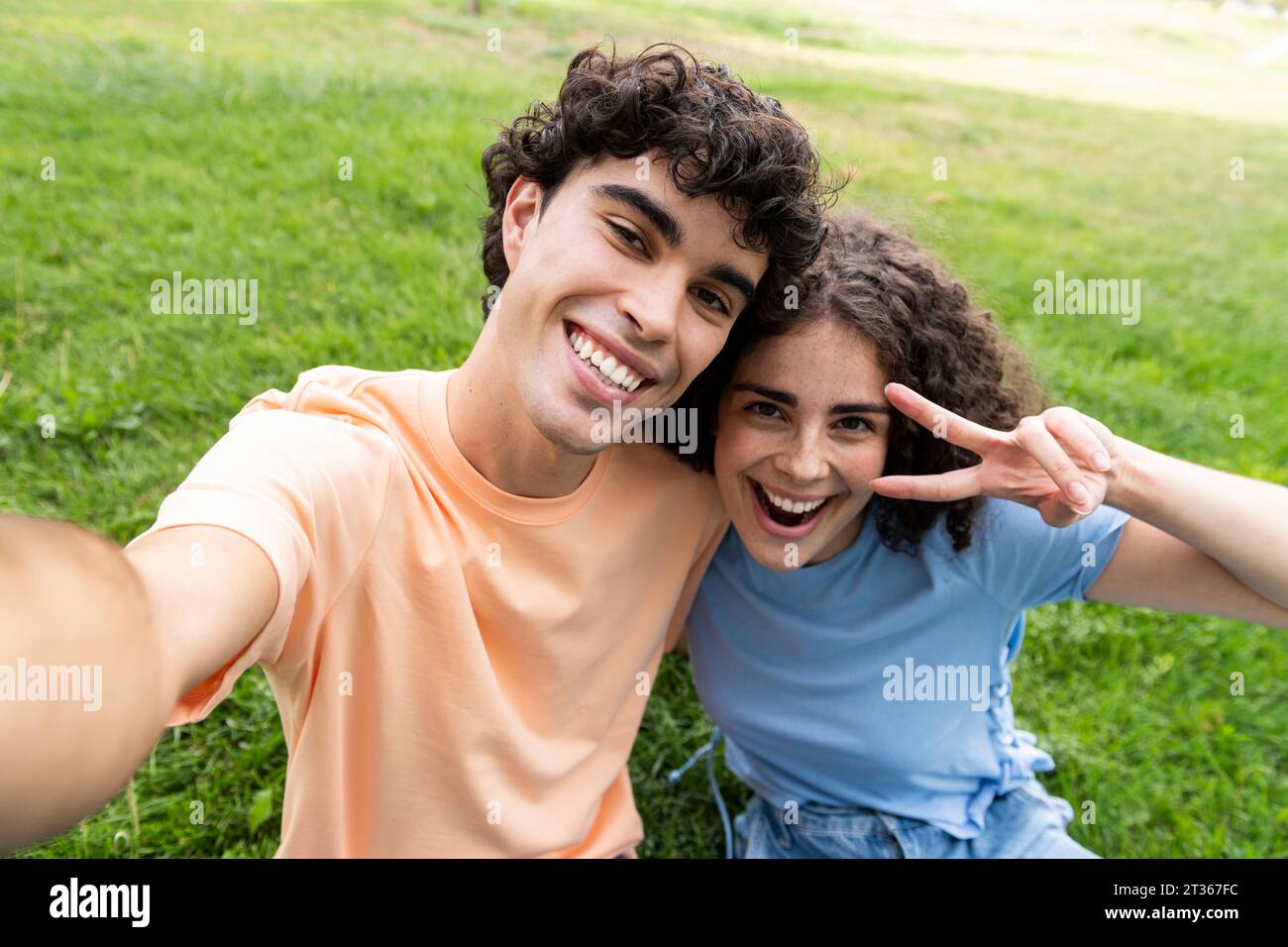 Happy boyfriend and girlfriend taking selfie on grass in park Stock ...