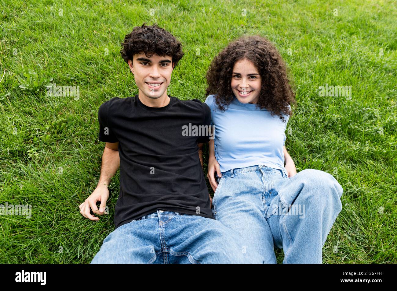 Happy young couple relaxing on grass Stock Photo
