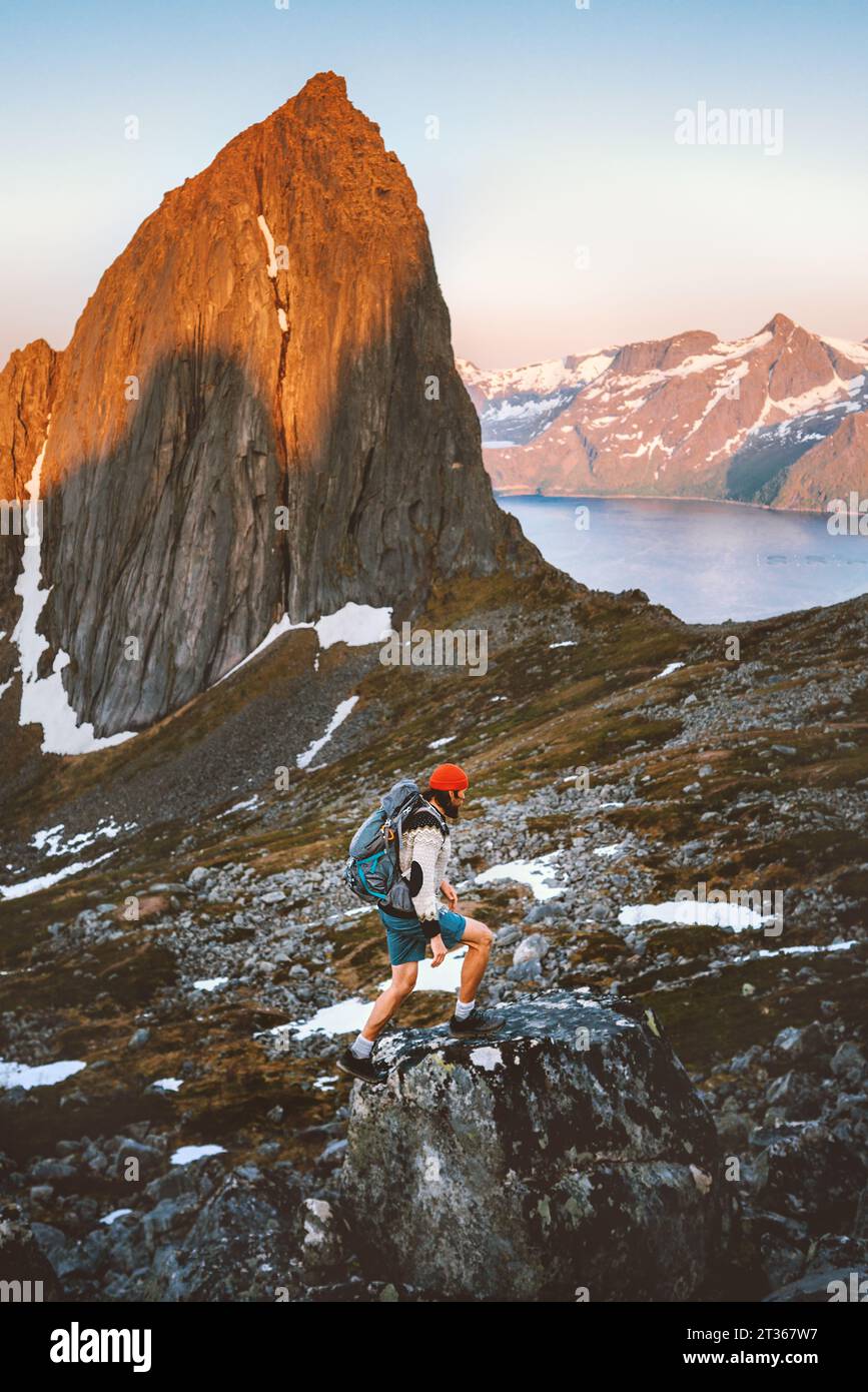 Man hiking alone in Norway mountains travel with backpack outdoor active vacations healthy lifestyle extreme sports exploring Senja island sunset Segl Stock Photo