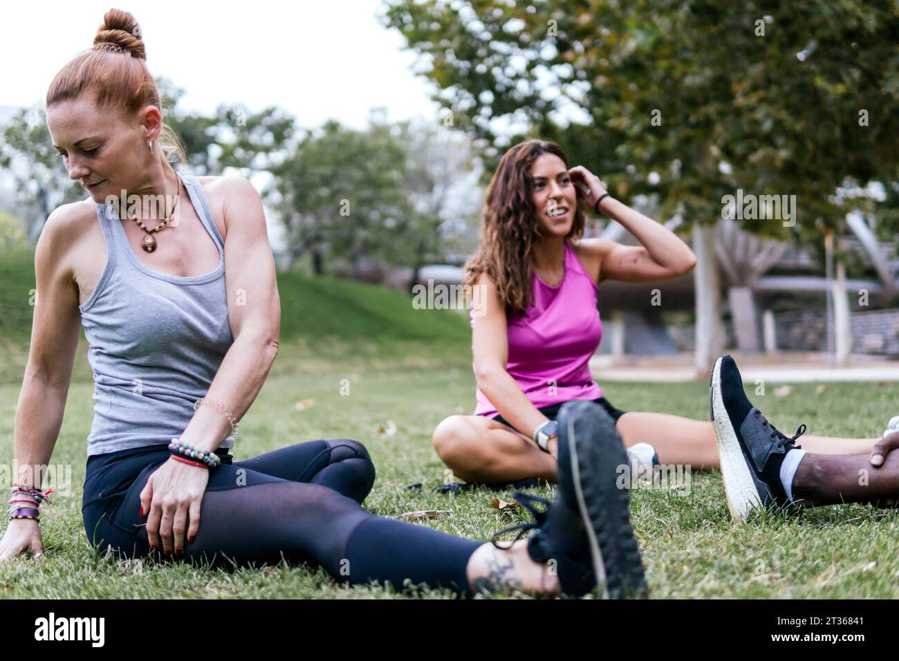 Multi-ethnic friends exercising on grass in park Stock Photo