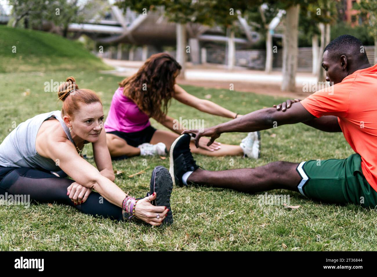 Multi-ethnic friends stretching and doing yoga in park Stock Photo