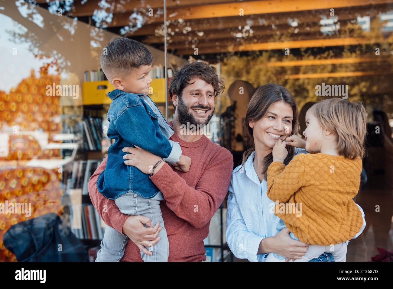 Happy mother and father spending leisure time with children in front of wall Stock Photo