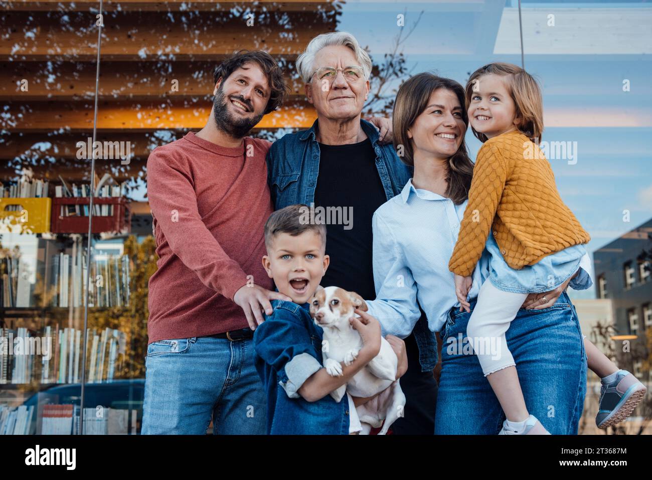 Happy family with dog in front of glass wall Stock Photo